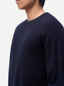 Person wearing a navy blue sweater against a white background. #color_navy