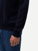 Person wearing a black long-sleeve shirt and blue jeans on a white background. #color_navy