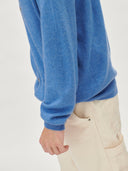 Blue sweater worn by a person on a light gray background. #color_blue