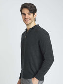 Man wearing a dark gray long-sleeve polo shirt on a light gray background