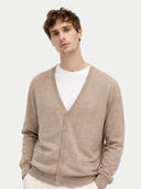 Man wearing a beige cardigan over a white shirt on a light gray background