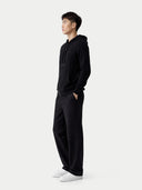 side view of a man wearing a black hoodie and pants on a white background. #color_black #ai-image