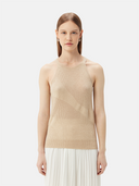 Shop GOBI Cashmere tops — woman in a beige sleeveless knit cashmere top and white pleated skirt