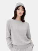 Person wearing a gray sweater and hat on a white background