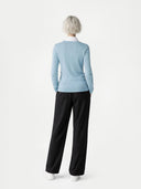 Person wearing a light blue jumper and black pants on a white background #color_black