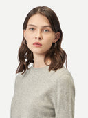 Woman wearing a gray sweater against a white background. #color_steel-silver