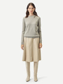 Woman wearing a gray sweater and beige skirt on a white background #color_steel-silver