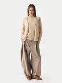 front view of a person wearing a beige v-neck cardigan over matching a sweater and pants on a white background