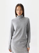 Woman wearing a gray turtleneck sweater on a white background