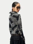 Person wearing a black and silver patterned jacket on a white background