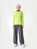 Person wearing a bright green sweater and gray pants on a white background #color_lime-yellow
