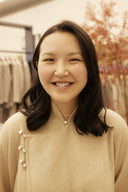 A smiling woman in a cream cashmere cardigan with pearl buttons