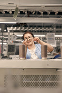 A GOBI knitting technician at a machine, threading cones of cashmere yarn