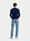 back view of a man wearing a navy sweater and light blue jeans on a white background. #color_dark-indigo #ai-image