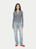 Woman wearing a gray cardigan and light blue jeans on a white background