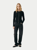 Woman wearing a black zip-up hoodie and black pants on a white background