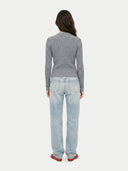 Person wearing a gray sweater and light blue jeans on a white background
