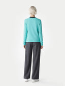 back view of a woman wearing a turquoise long-sleeve top and gray pants on a white background. #color_aqua-green #ai-image