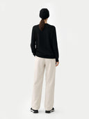 Person wearing a black sweater and white pants on a white background