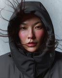 A woman in a hooded dark CashmereTech parka, hair caught in the wind