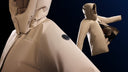 Beige CashmereTech puffer jackets suspended against a dark background