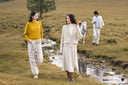 Two women in GOBI cashmere knitwear walk beside a stream on the Mongolian steppe as a man leads a white horse behind them