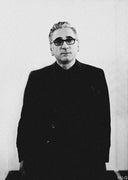 Saverio Palatella in sunglasses and a black coat, grainy black-and-white portrait