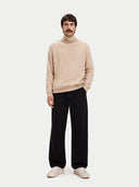 Man wearing a beige sweater and black pants on a white background. #color_beige #ai-image