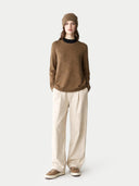Person wearing a brown sweater and beige pants on a white background #color_lead-gray