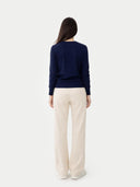 Woman wearing a navy jumper and beige pants on a white background #color_beige