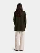 Person wearing a dark green coat and beige pants on a white background #color_olive-green