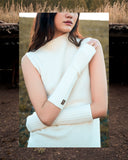 Woman in a cream sleeveless cashmere turtleneck and ribbed arm warmers