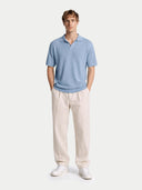 Man wearing a light blue polo shirt and beige pants on a white background #color_celestial-blue