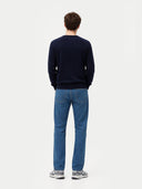 Man wearing a navy sweater and blue jeans on a white background. #color_navy #ai-image