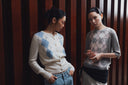 Two women in pale blue and grey argyle cashmere cardigans against wooden panelling