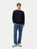 Man wearing a navy sweater and blue jeans on a white background. #color_navy #ai-image