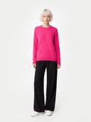 Person wearing a bright pink sweater and black pants on a white background #color_magenta