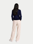 back view of a woman wearing a navy sweater and beige pants on a white background. #color_dark-indigo #ai-image