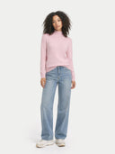 front view of a woman wearing a pink sweater and light blue jeans on a white background