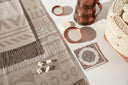 A patterned GOBI cashmere throw laid out with copper bowls and carved traditional Mongolian boxes