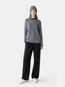Person wearing a gray sweater and black pants on a white background