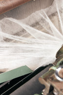 A thin white web of carded cashmere fibre coming off a carding machine