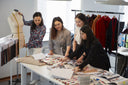Four GOBI designers around a table comparing cashmere fabric swatches beside a dress form
