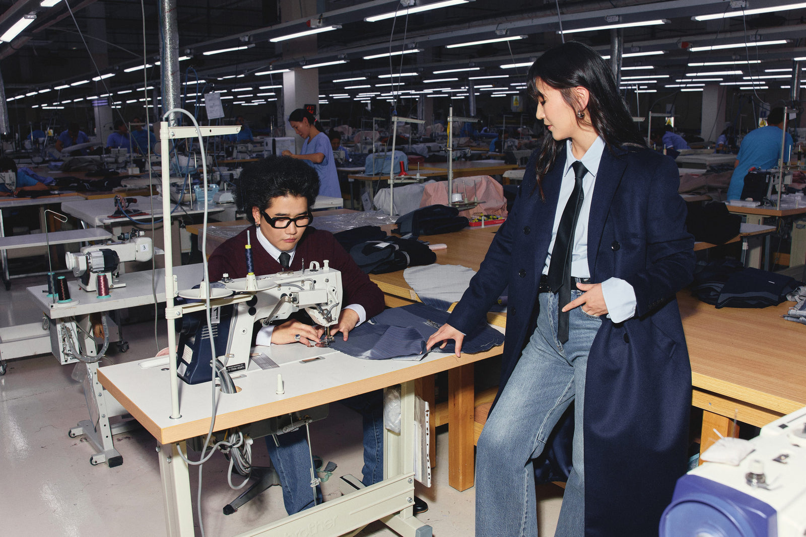 A GOBI sewing floor in Ulaanbaatar — a machinist at a sewing machine with a designer in a navy coat alongside