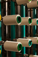Cones of natural cashmere yarn loaded on a weaving creel