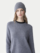 Woman wearing a gray sweater and matching beanie on a light gray background