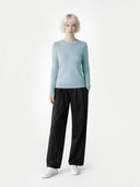 Person wearing a light blue jumper and black pants on a white background #color_black