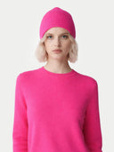 Person wearing a bright pink beanie and sweater on a light gray background