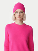 Person wearing a bright pink beanie and sweater on a light gray background #color_magenta