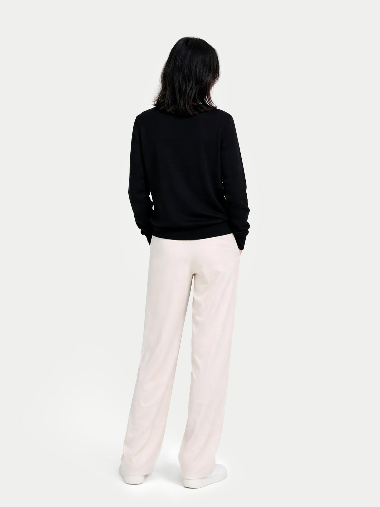 Person wearing a black sweater and light pink pants on a white background